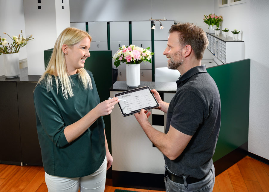 Erster Termin - Helferin zeigt Patienten, wie man die Anamnese am Tablet ausfüllt - Zahnarzt und Fachzahnarzt Praxis Guntermann, Olpe. Foto Dietrich Hackenberg