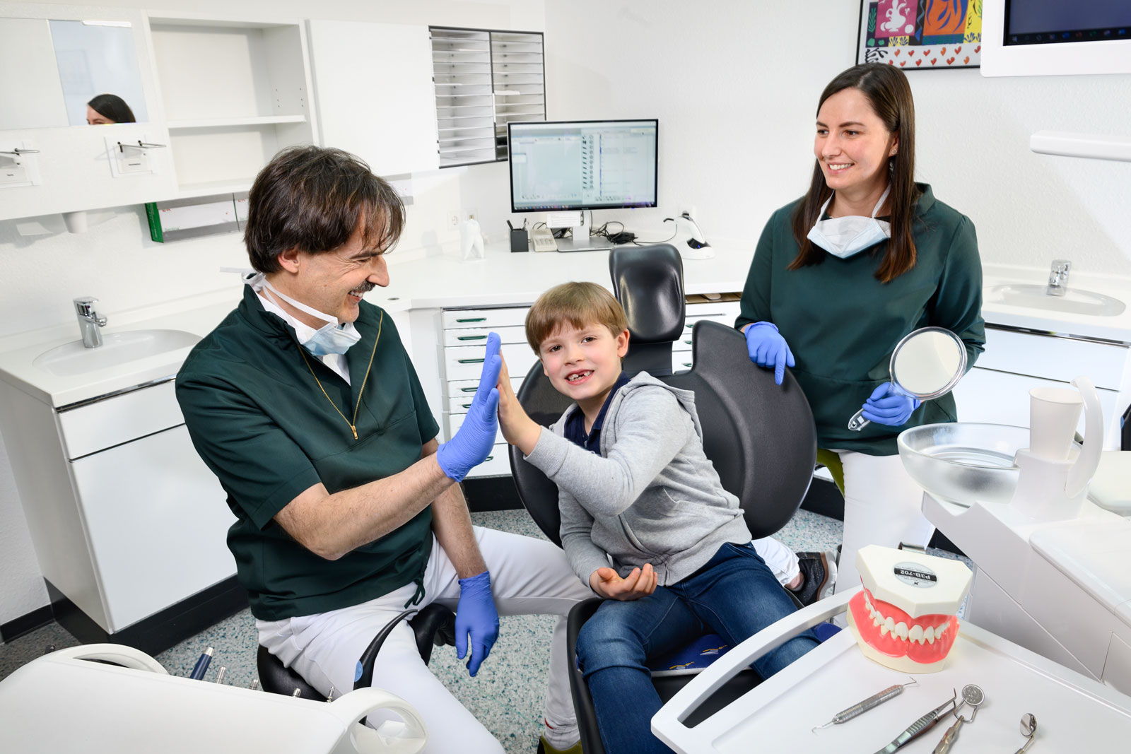 Zahnarzt klatscht sich ab mit Kinderpatienten - Kinderzahnheilkunde - Zahnarzt und Fachzahnarzt Praxis Guntermann, Olpe. Foto Dietrich Hackenberg