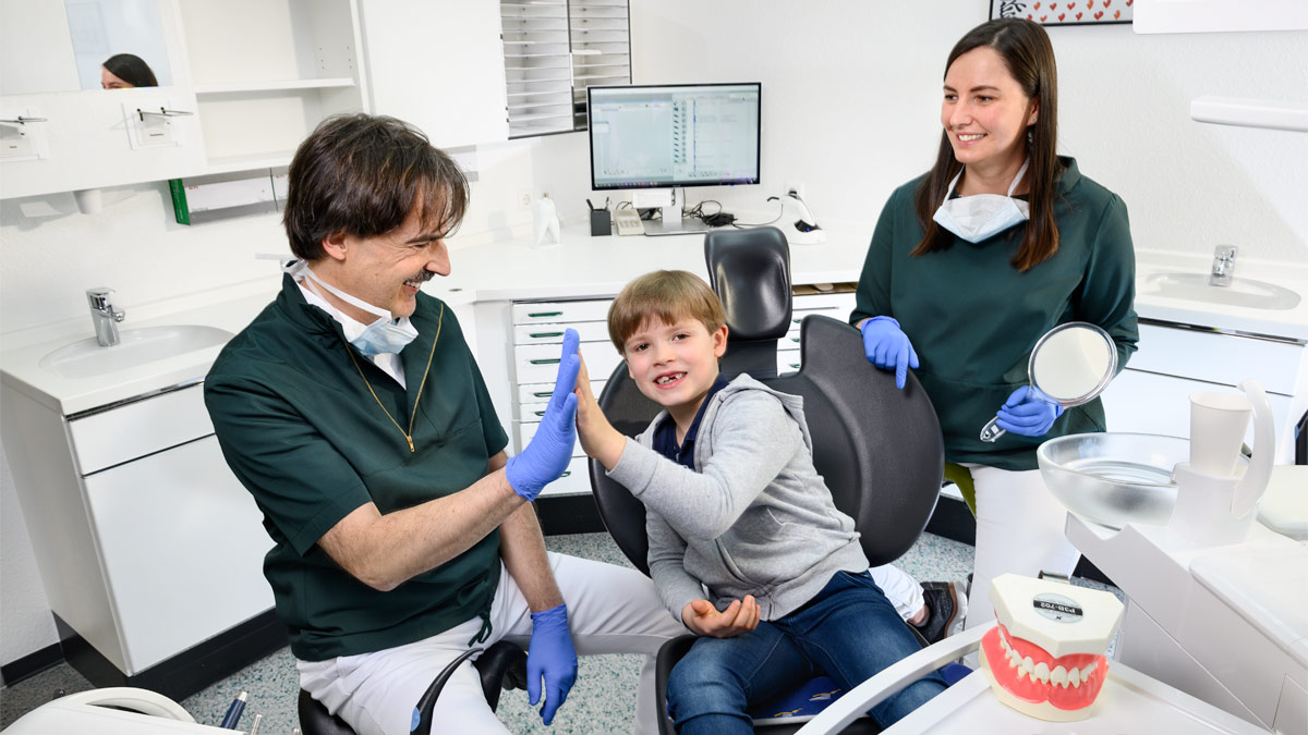 Zahnarzt klatscht sich ab mit Kinderpatienten - Kinderzahnheilkunde - Zahnarzt und Fachzahnarzt Praxis Guntermann, Olpe. Foto Dietrich Hackenberg