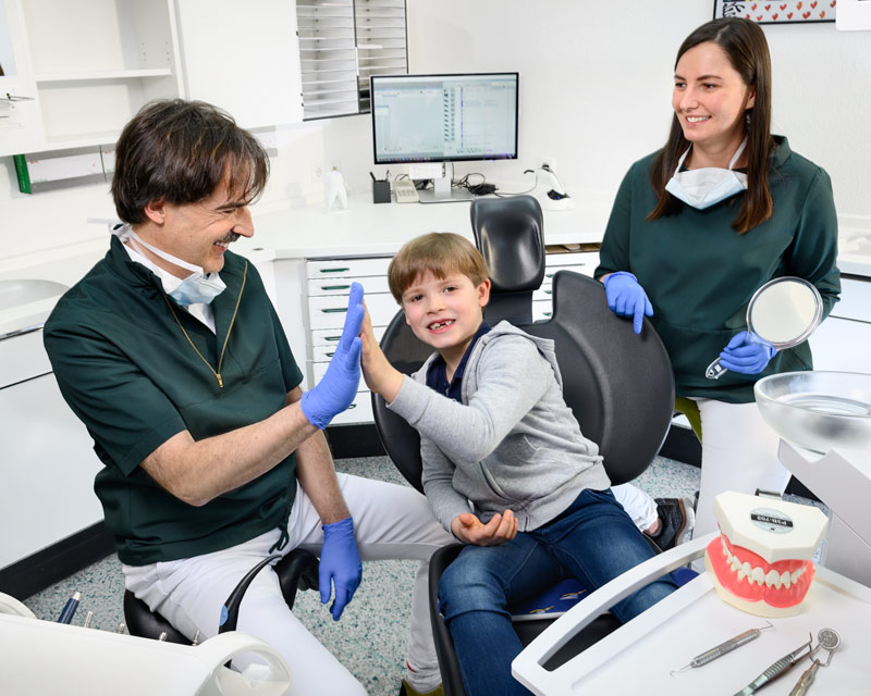 Zahnarzt klatscht sich ab mit Kinderpatienten - Kinderzahnheilkunde - Zahnarzt und Fachzahnarzt Praxis Guntermann, Olpe. Foto Dietrich Hackenberg