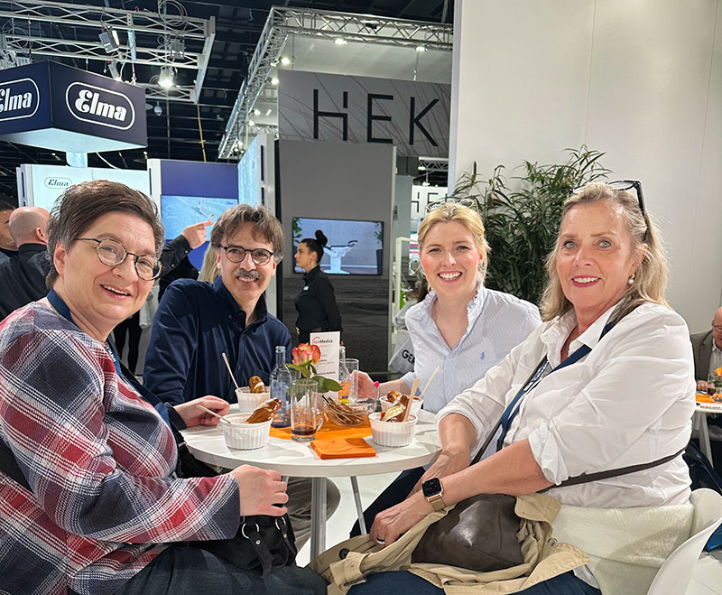 Zahnärzte und zwei Mitarbeiterinnen an einem Tisch auf der Internationalen Dental-Schau (IDS) in Köln