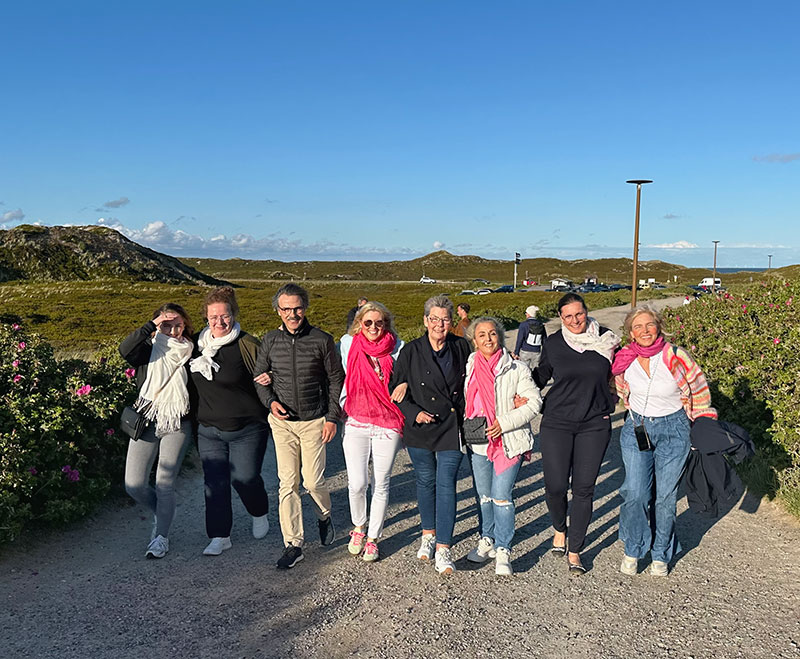 Team in einer Reihe untergefasst auf Strandweg