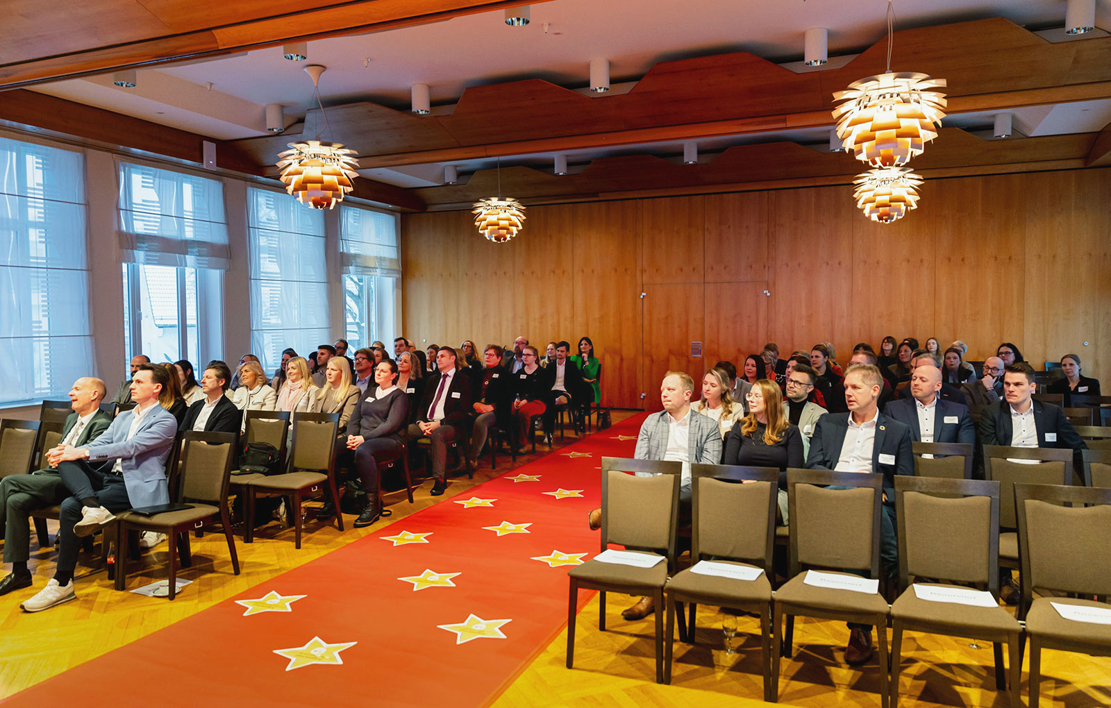 Publikum bei der Verleihung des Siegels „Familienfreundliches Unternehmen“ in der Mitte der rote Teppich Sternen bei der Abschlussveranstaltung im Haus der Siegerländer Wirtschaft in Siegen. Foto: Kreisverwaltung Siegen-Wittgenstein