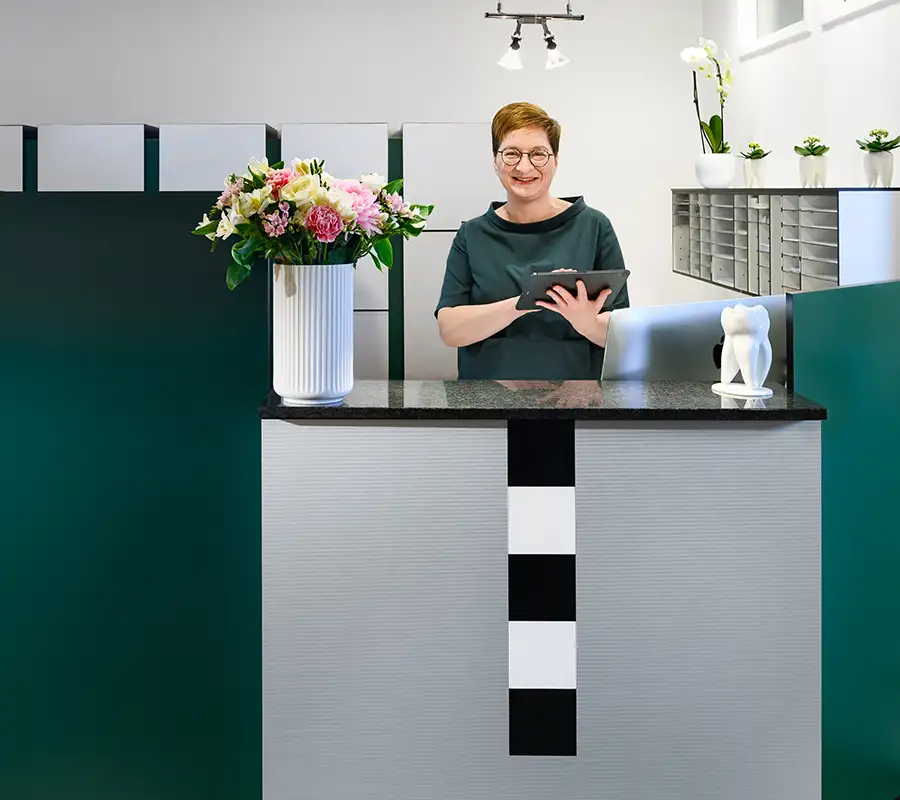 Helferin mit Tablet hinter dem Empfangstresen