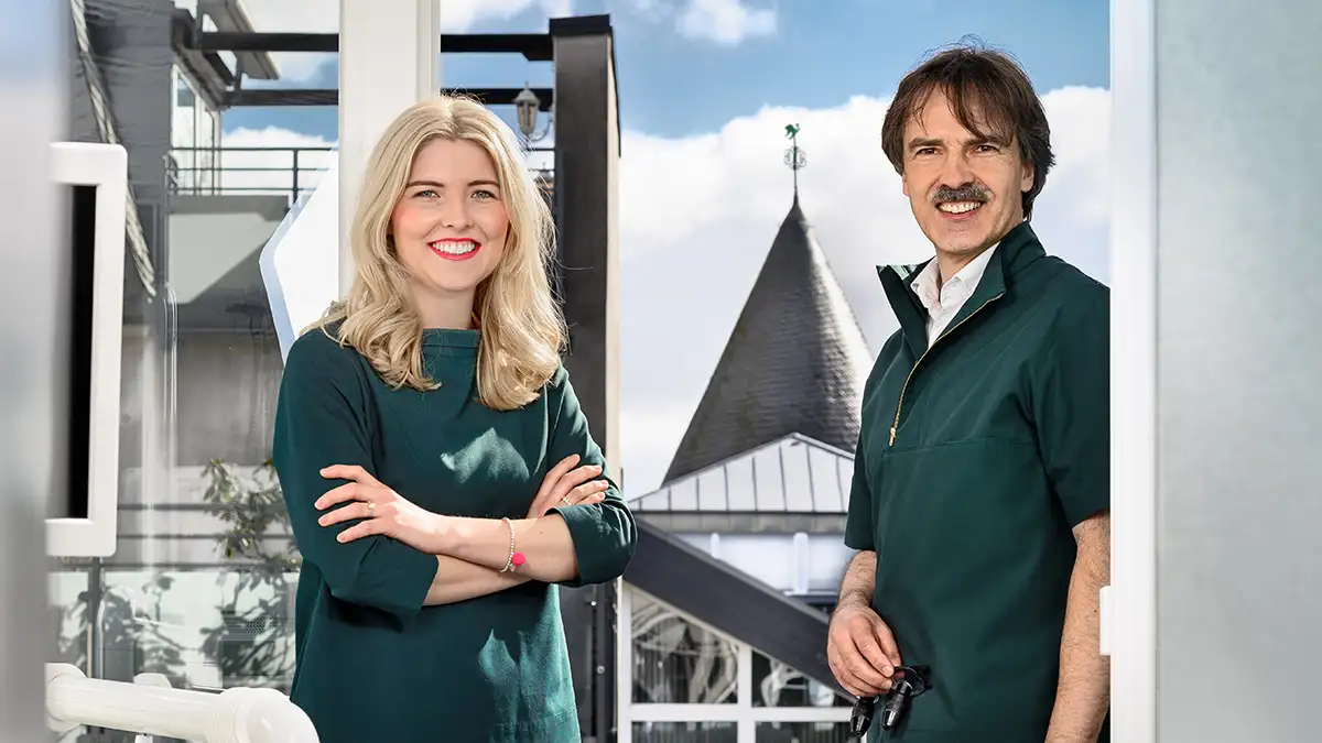 Zahnärztin Leona Guntermann und Fachzahnarzt Peter guntermann stehen am Fenster des Behandlungszimmers - im Hintergrund der Olper Hexenturm