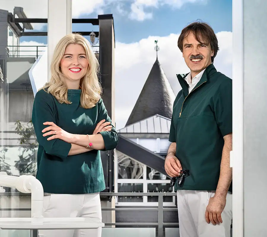 Zahnärztin Leona Guntermann und Fachzahnarzt Peter guntermann stehen am Fenster des Behandlungszimmers - im Hintergrund der Olper Hexenturm
